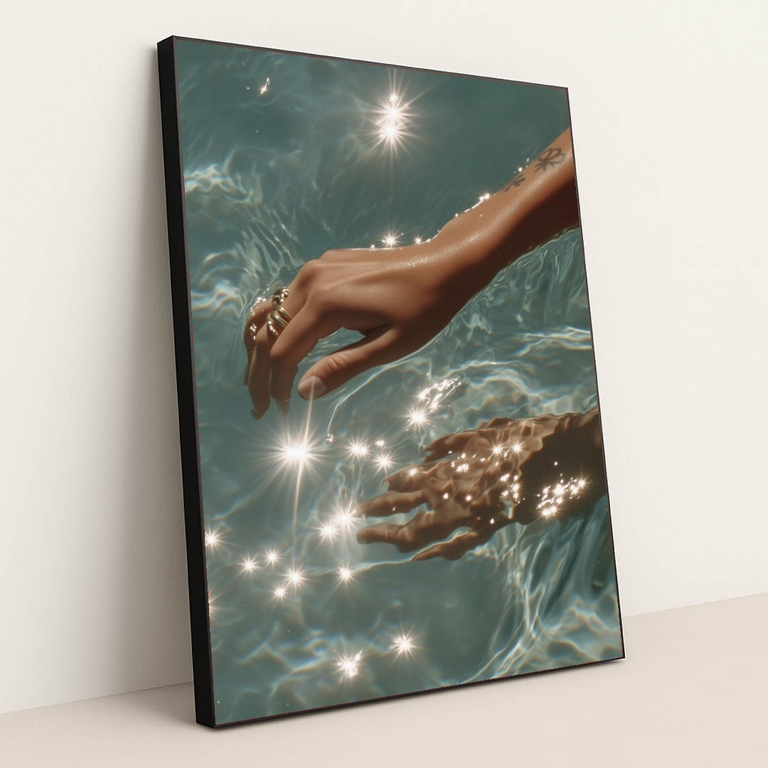 This artwork features a hand with rings reaching into sparkling blue water, in a black frame.