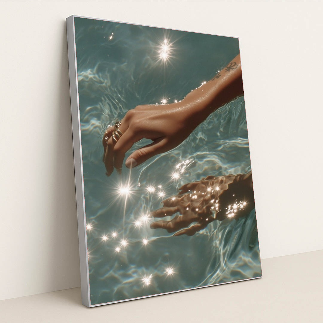 This artwork features a hand with rings reaching into sparkling blue water, in a silver frame.