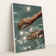 This artwork features a hand with rings reaching into sparkling blue water, in a white frame.