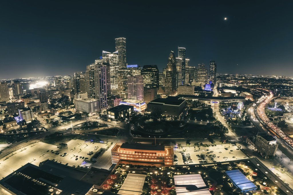 Erik Mclean - A stunning aerial view of a city skyline illuminated at night, showcasing modern skyscrapers and bustling streets.