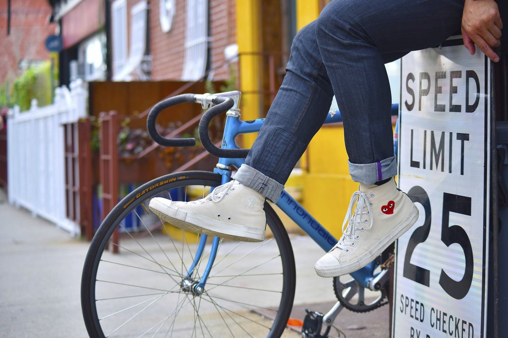 Collis - Close-up of sneakers next to a bike and speed limit sign in Brooklyn, NY.