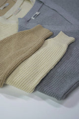 Ron Lach - A collection of folded knit sweaters in earthy tones displayed in a flat lay arrangement.