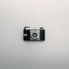 Alex Andrews - A classic Kodak camera displayed centrally on a minimalist white background.