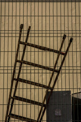 Victor  Moragriega - A rusty ladder leaning against a metal fence, creating an urban aesthetic with a vintage mood.
