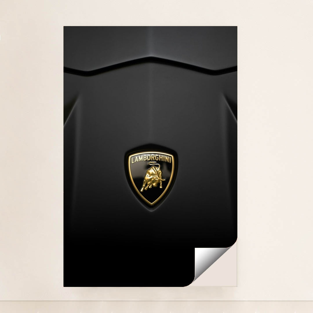 This photo shows a close-up of a Lamborghini badge on a matte black car hood, unframed.