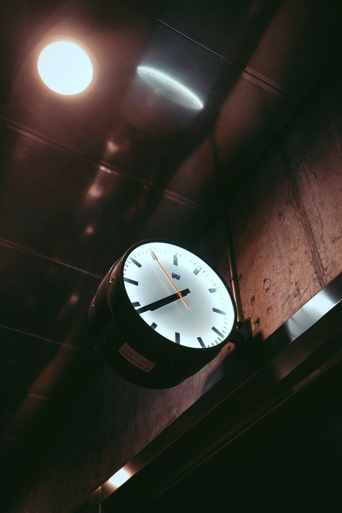 Nathan J Hilton - A low-angle view of a wall clock under warm lighting, evoking a sense of time and mystery.