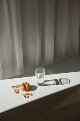 Cup of  Couple - A minimalist scene with a peeled orange and a glass of water casting shadows.