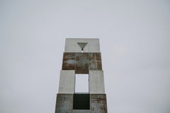 Emre  Akyol - Low angle view of a geometric concrete structure with a minimalistic design against a pale sky.