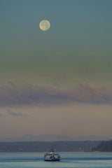 JOHN CALLERY - A serene scene of a ferry on calm waters under a full moon at twilight in Steilacoom, WA.