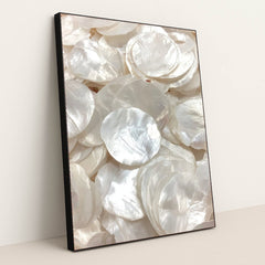 This artwork shows glossy, layered white capiz shells in soft light, in a black frame.