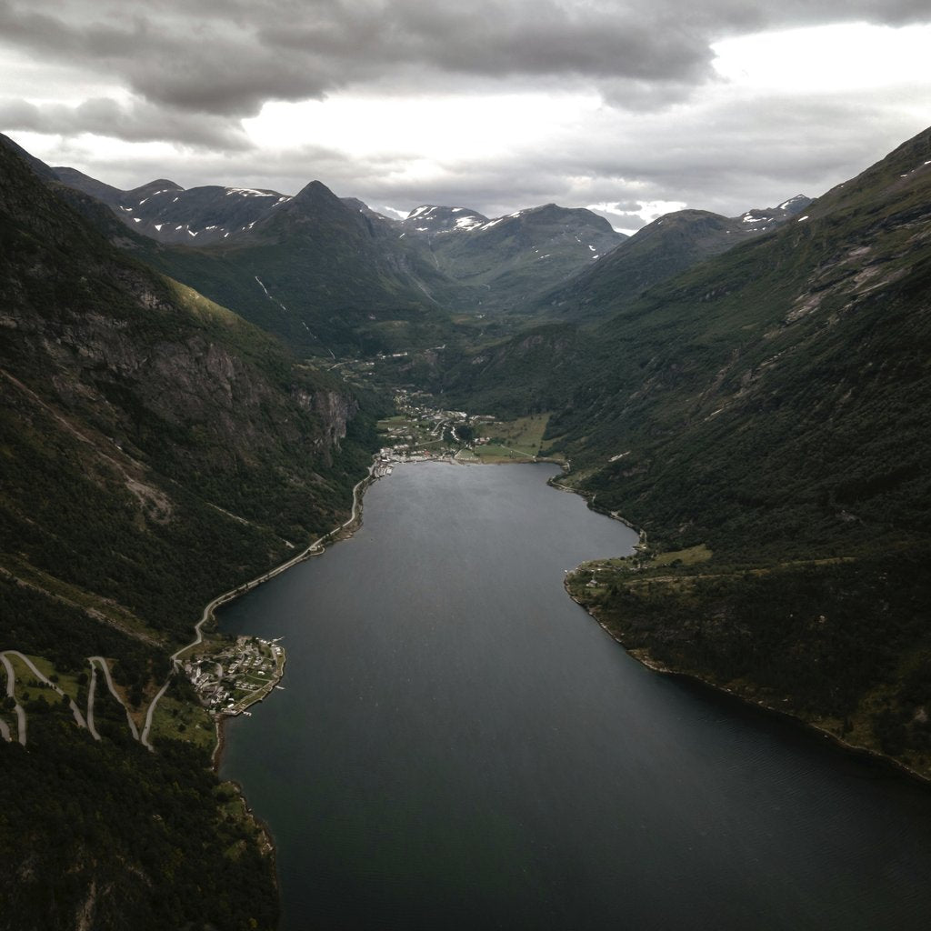 Roberto Shumski - Stunning aerial view of a serene valley and lake in Norway, surrounded by majestic mountains.