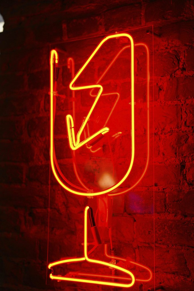 Nadin Sh - Red neon wineglass sign glowing against a rustic brick wall.