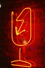 Nadin Sh - Red neon wineglass sign glowing against a rustic brick wall.