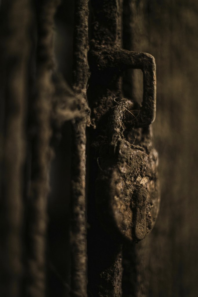 KNKO Photography - Close-up of a rusty padlock on a dusty wooden gate, symbolizing security decay.