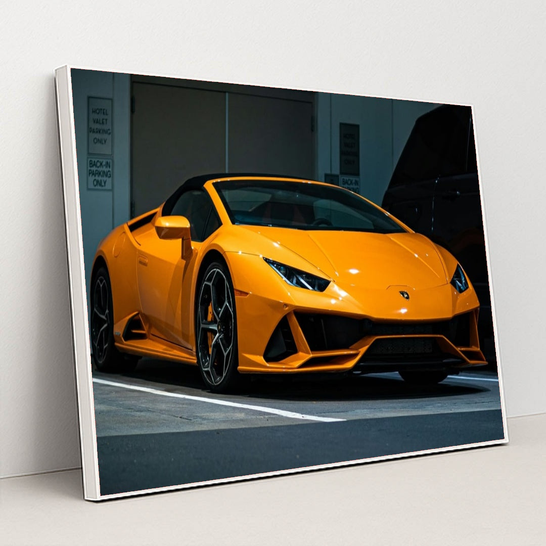 This photo shows an orange Lamborghini Huracán Spyder parked in a valet area at night, in a white frame.