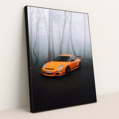 This photo shows an orange Porsche sports car parked on a misty forest road, in a black frame.