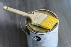 Mian Rizwan - A close-up image of a paintbrush resting on a paint can, ideal for DIY projects.