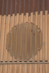 Victor  Moragriega - Close-up of an aged wooden facade featuring a circular pattern with weathered texture.