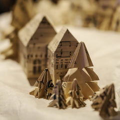 Arkay . - A close-up of a handmade origami Christmas village featuring paper trees and houses.