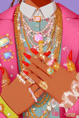 This artwork shows hands with red nails adorned with multiple sparkling gold and silver rings and necklaces over a pink jacket, unframed.