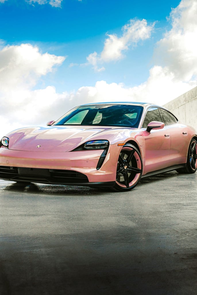 Pink Porsche Taycan Beneath Fluffy Skies showcasing vibrant color against a bright blue sky, ideal for car wall art.
