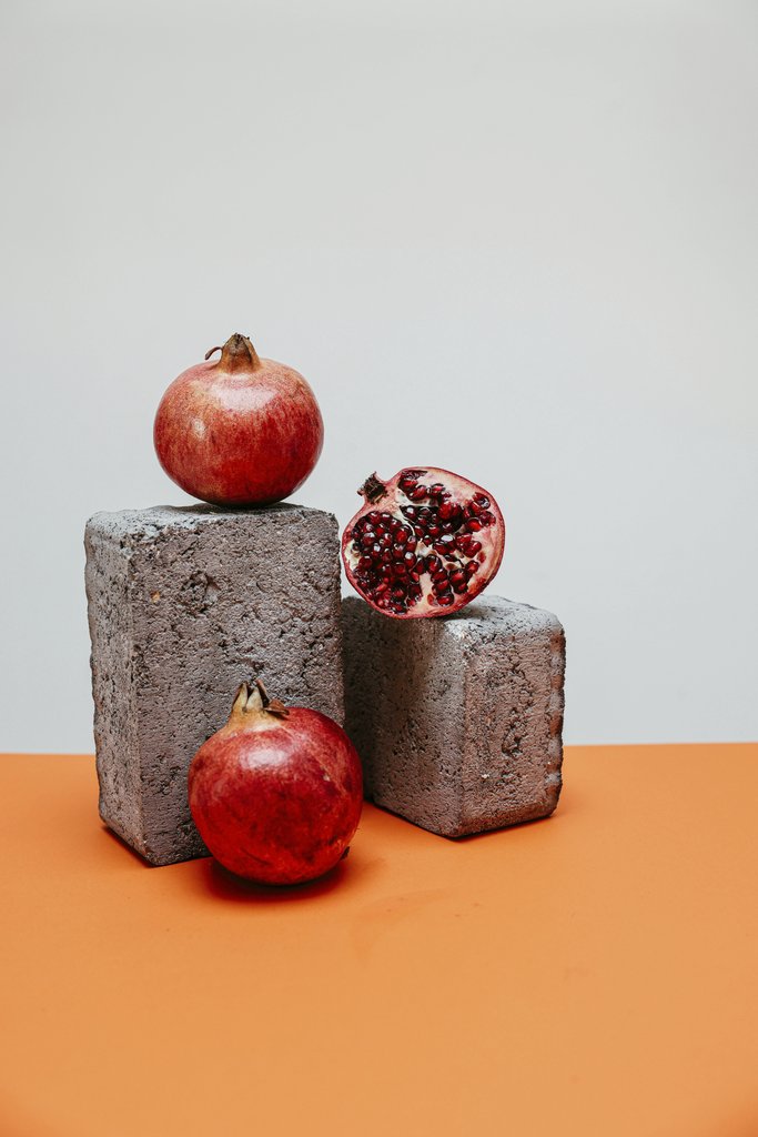 Cup of  Couple - A minimalist still life image featuring pomegranates artfully arranged on concrete blocks.