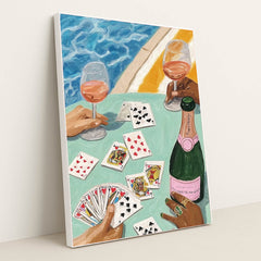 This artwork features two hands holding wine glasses, playing cards, and a bottle of rosé by a pool, in a white frame.