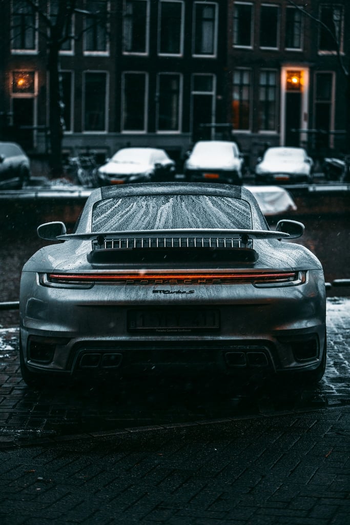 Porsche 911 Turbo S in Winter Streets, showcasing LED taillights and active rear wing on a snow-dusted street.
