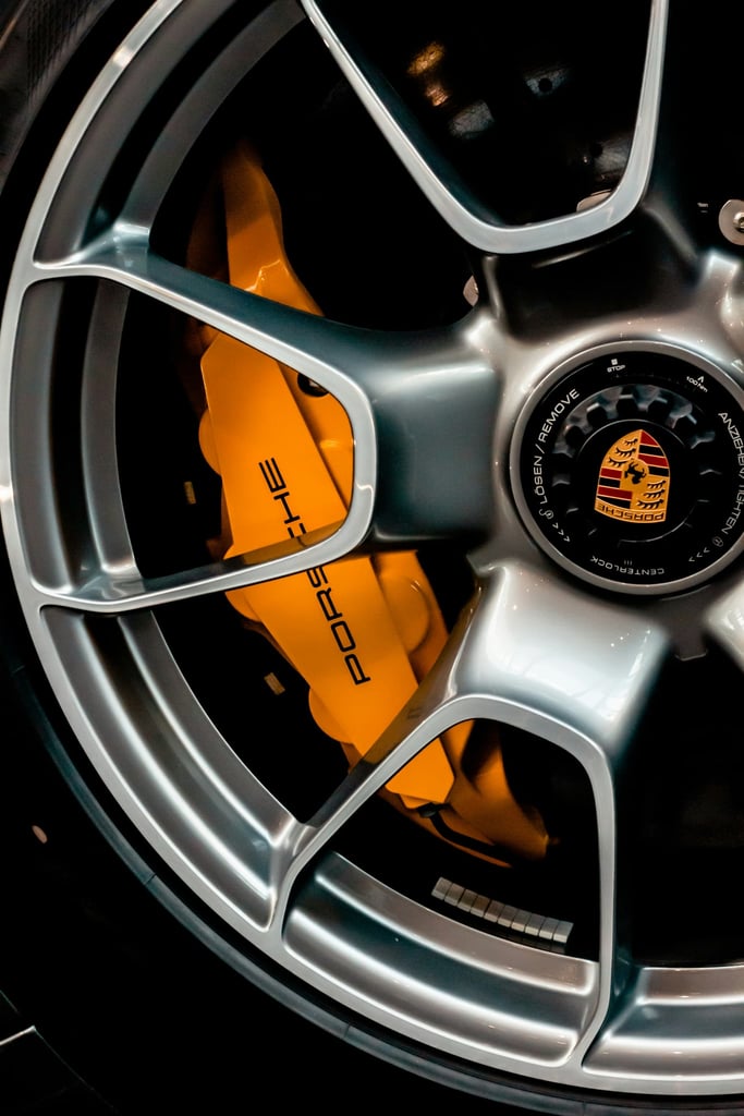 Close-up of a Porsche Precision Wheel showcasing satin silver alloy with bold yellow brake calipers for car wall art.