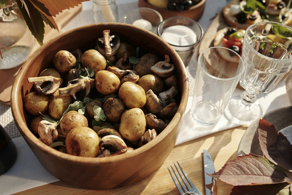 Askar Abayev - A rustic bowl of baby potatoes and mushrooms on a sunny dining table setting.