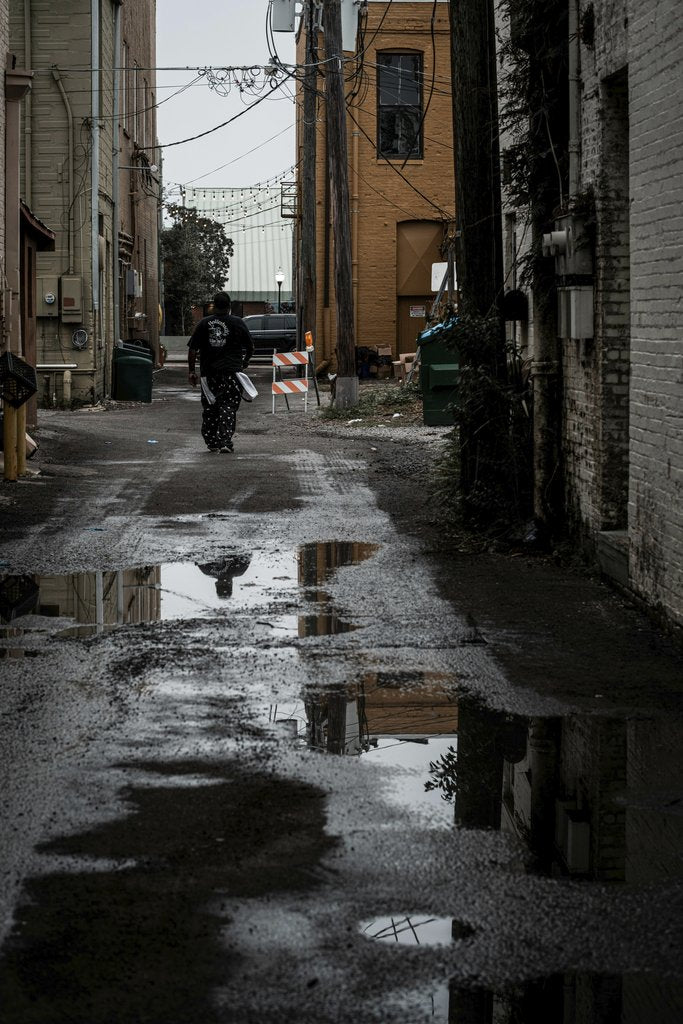 Connor McManus - A dark, moody alleyway after rain featuring a solitary figure and puddle reflections.