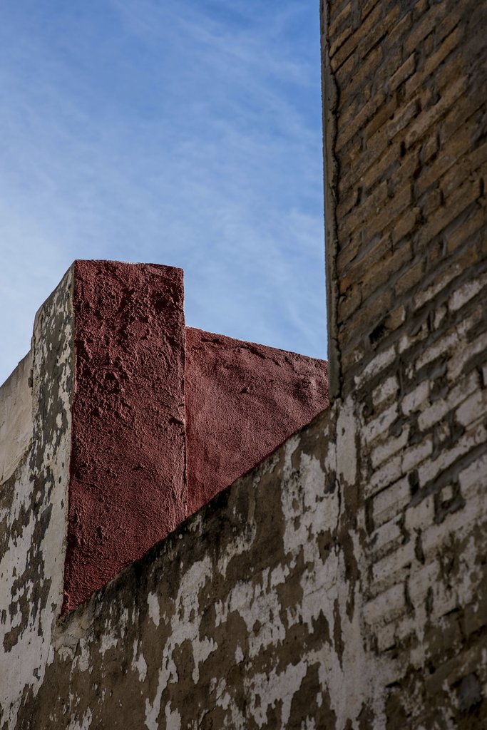 Victor  Moragriega - Rustic brick walls meeting under a bright blue sky. Urban architectural detail.
