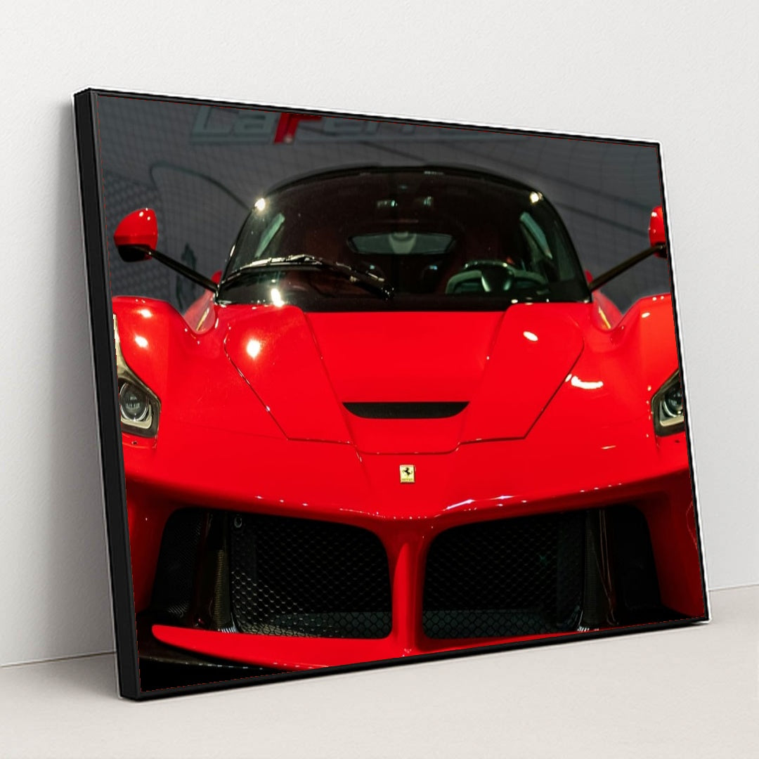 This photo shows the front view of a red Ferrari LaFerrari at an indoor car show, in a black frame.