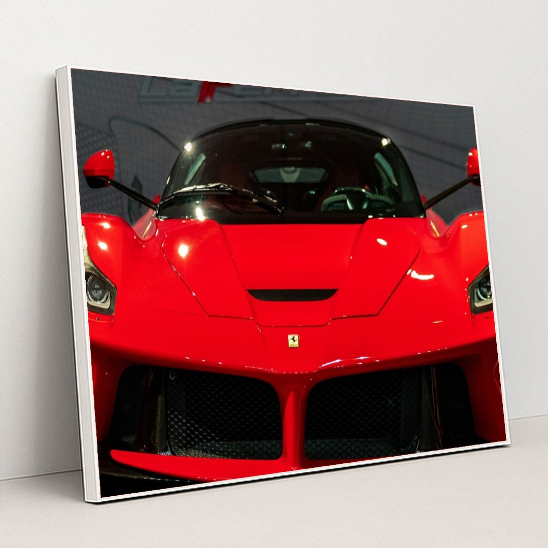 This photo shows the front view of a red Ferrari LaFerrari at an indoor car show, in a white frame.