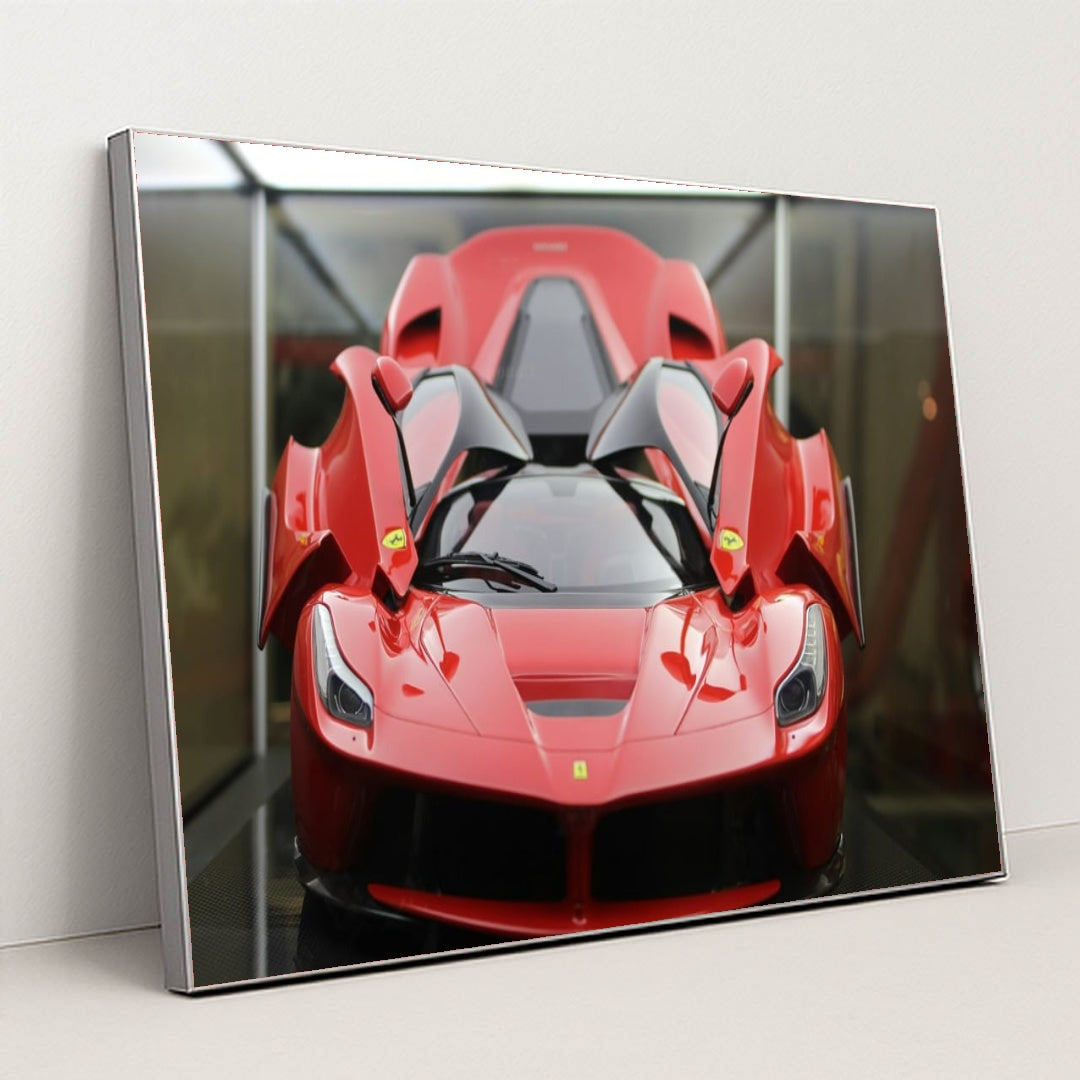 This photo shows a red Ferrari LaFerrari with scissor doors open, displayed indoors under soft lighting, in a silver frame.