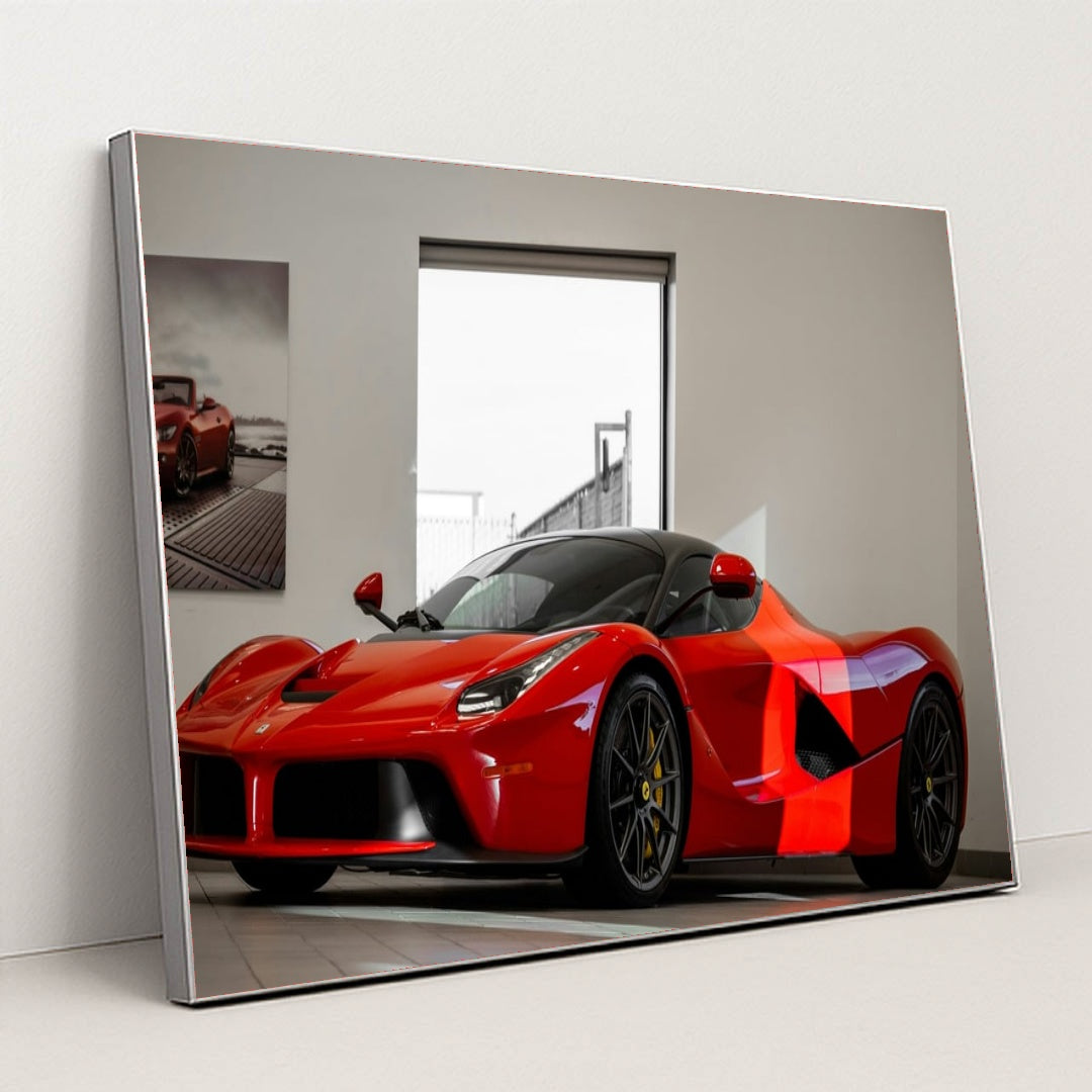 This photo shows a red Ferrari LaFerrari coupe displayed in a bright, modern showroom, in a silver frame.