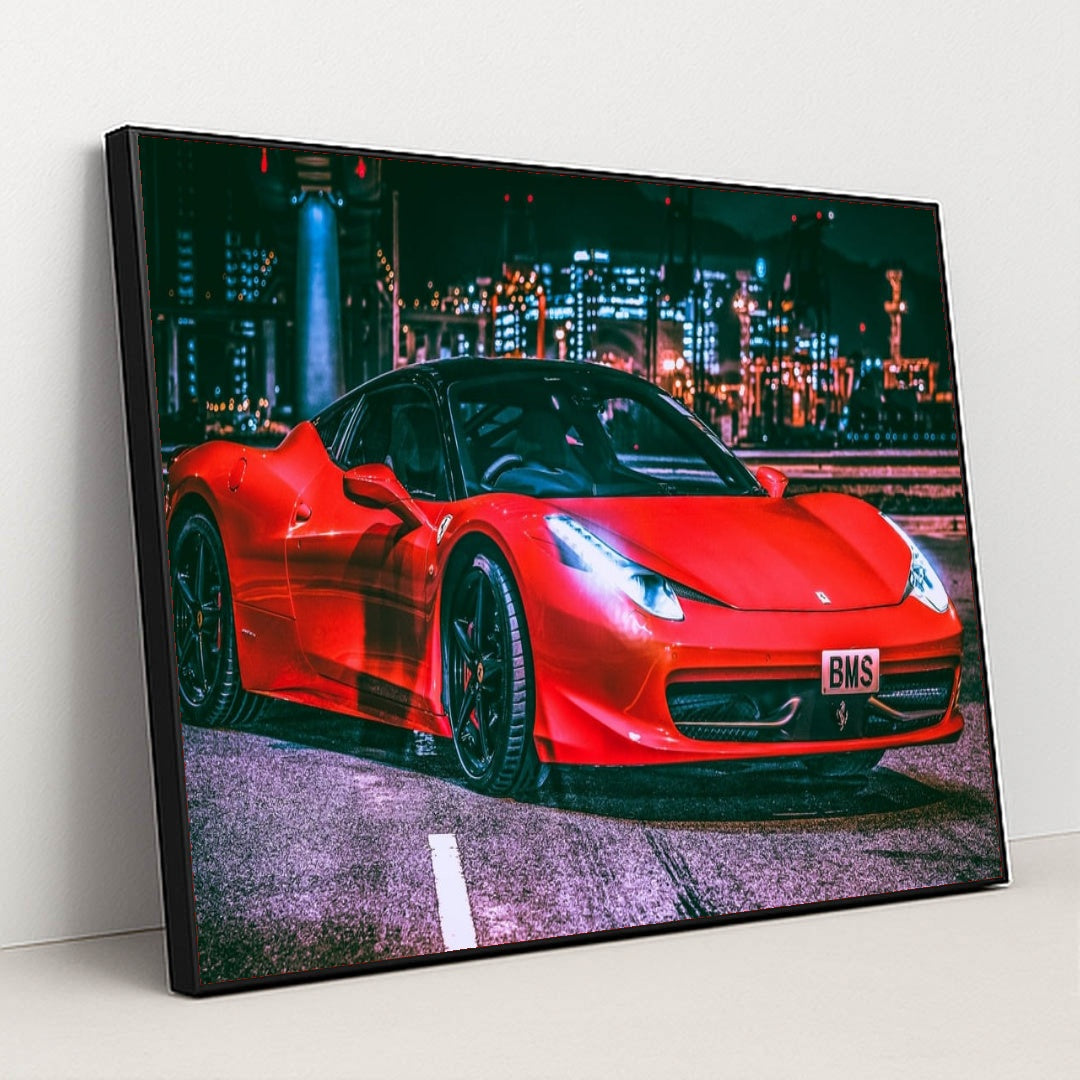 This photo shows a red Ferrari 458 Italia with black wheels parked under city lights at night, in a black frame.