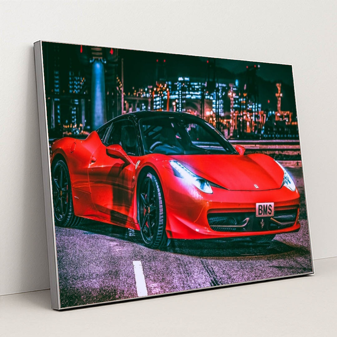 This photo shows a red Ferrari 458 Italia with black wheels parked under city lights at night, in a silver frame.