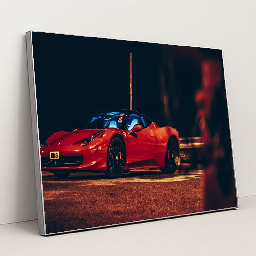 This photo shows a red Ferrari sports car parked at night under orange streetlights, with a blue-lit interior, in a silver frame.