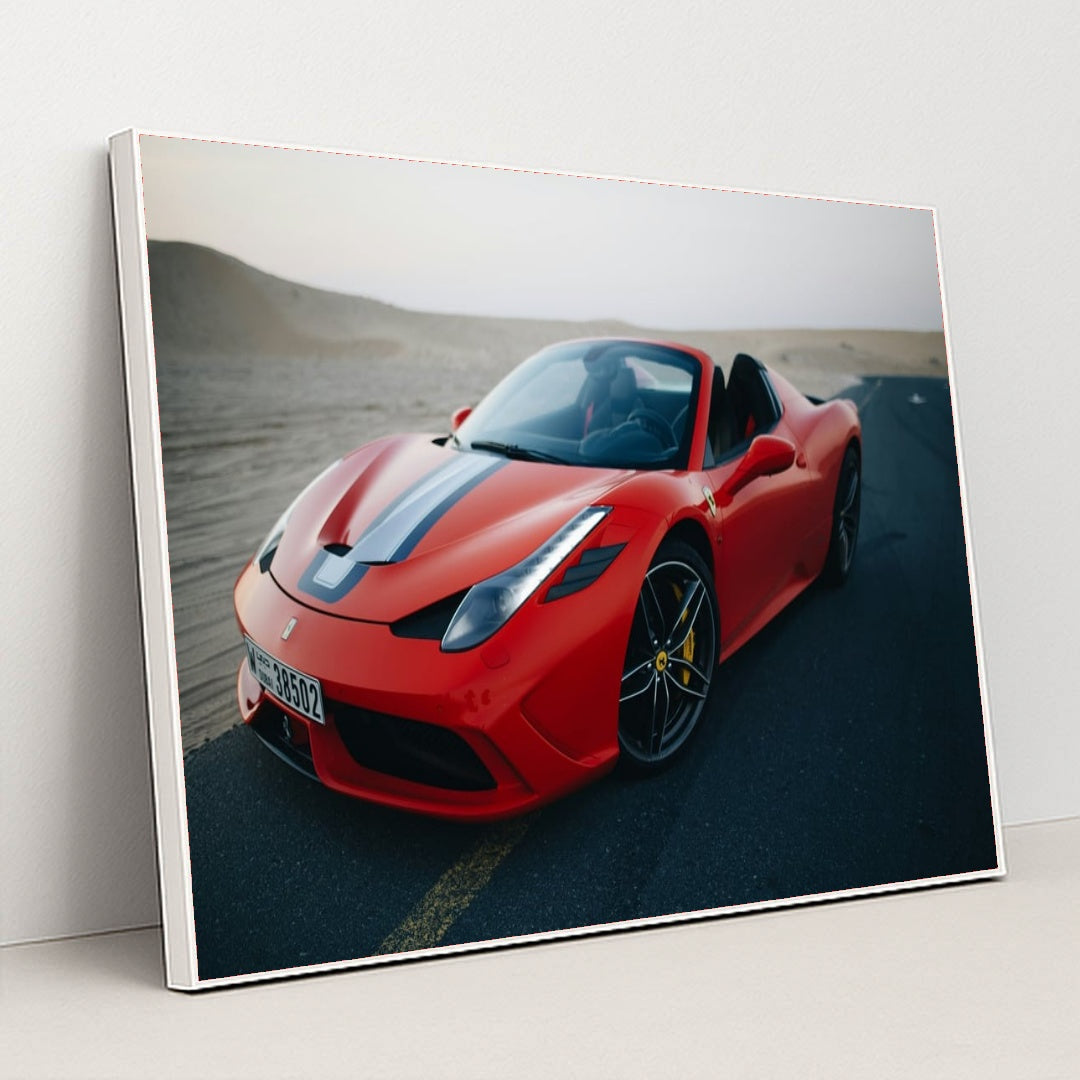This photo shows a red Ferrari convertible with a blue-and-white racing stripe parked on an empty desert road at dusk, in a white frame.