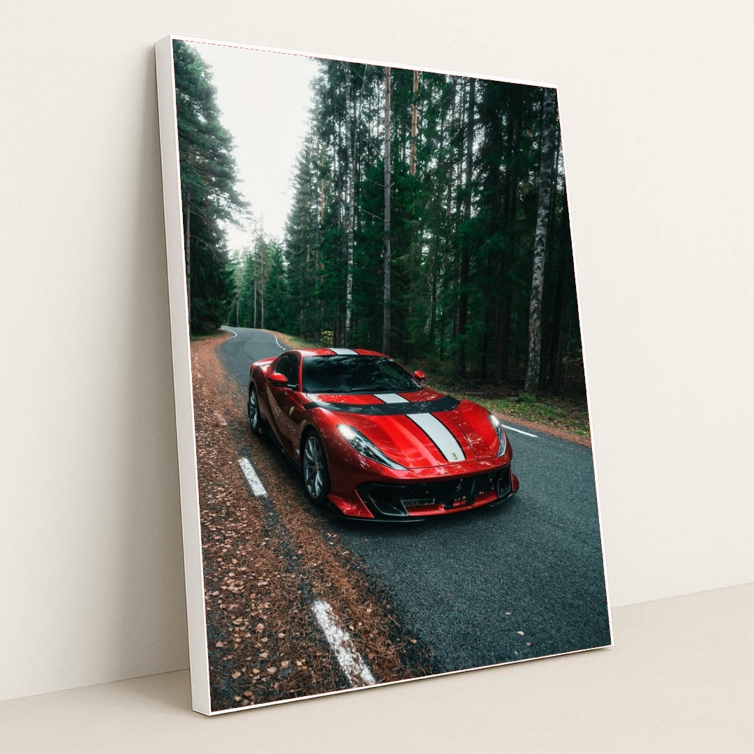 This photo shows a red Ferrari 812 Competizione with a white racing stripe parked on a winding forest road, in a white frame.
