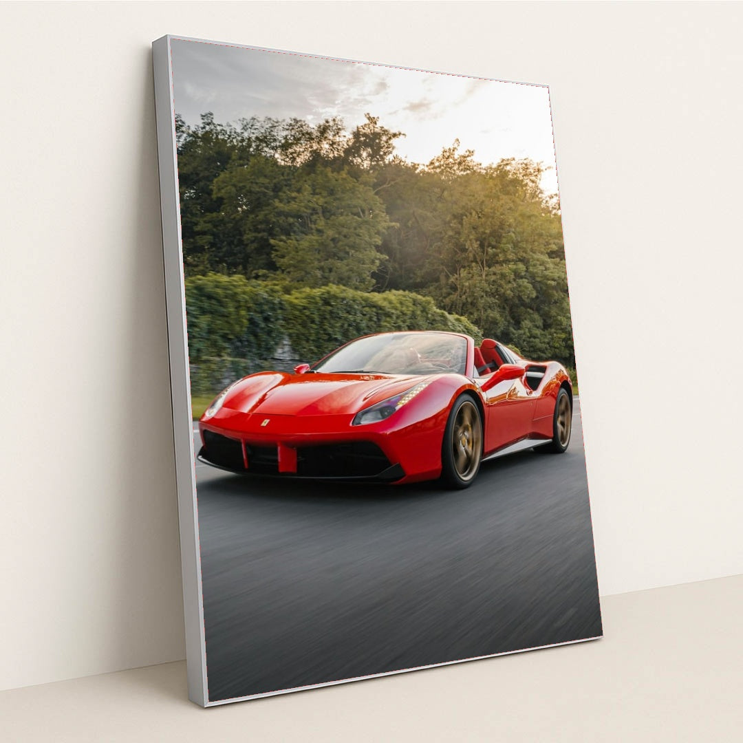 This photo shows a red Ferrari 488 Spider driving on a road with trees in the background, in a silver frame.
