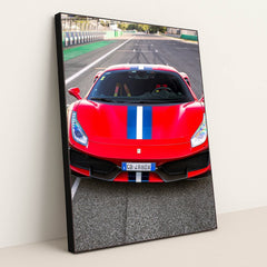 This photo shows the front view of a red Ferrari 488 Pista with a blue and white racing stripe parked on a racetrack, in a black frame.