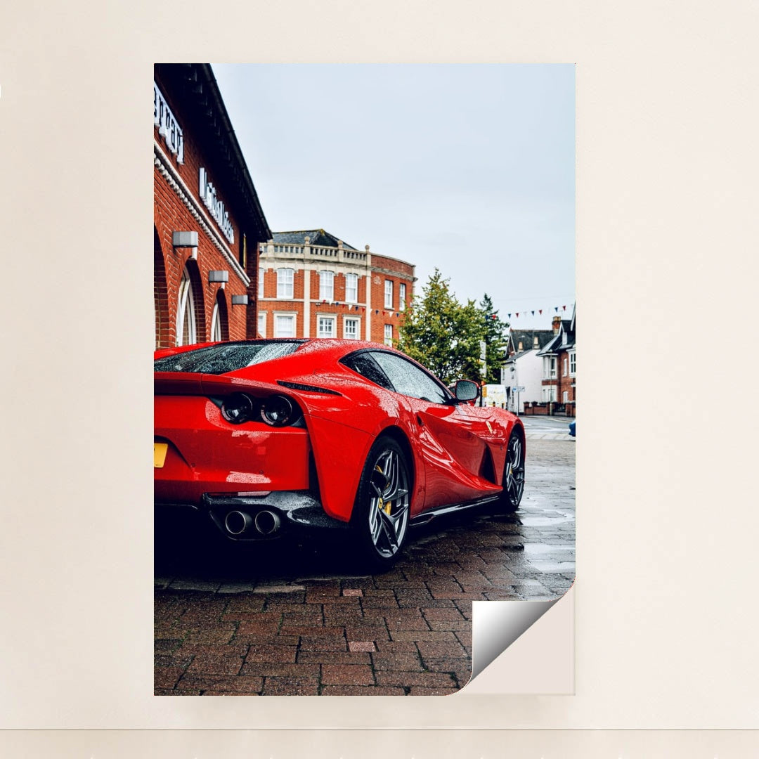 This photo shows the rear three-quarter view of a red Ferrari 812 Superfast parked on a wet city street, unframed style.
