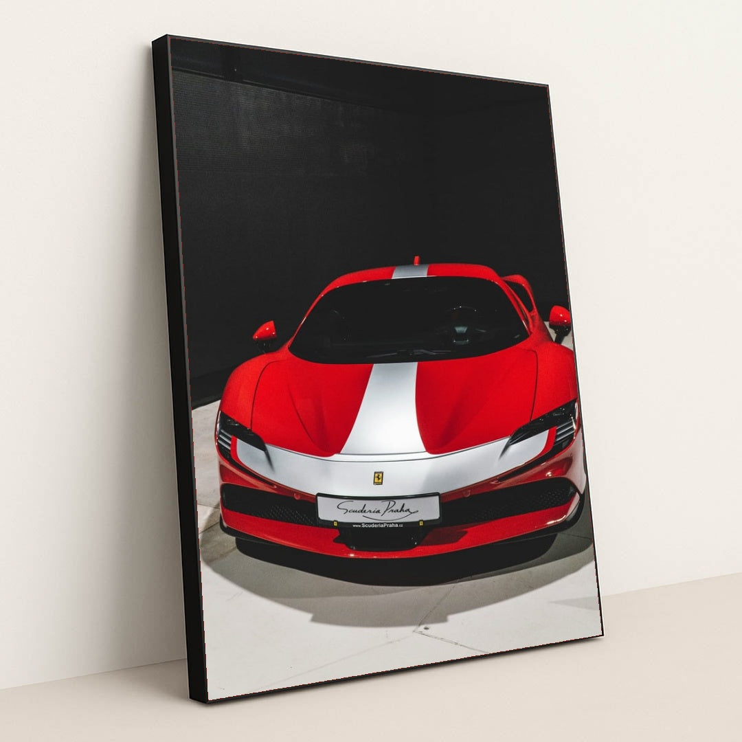 This photo shows a red Ferrari sports car with a white racing stripe parked indoors under direct lighting, in a black frame.