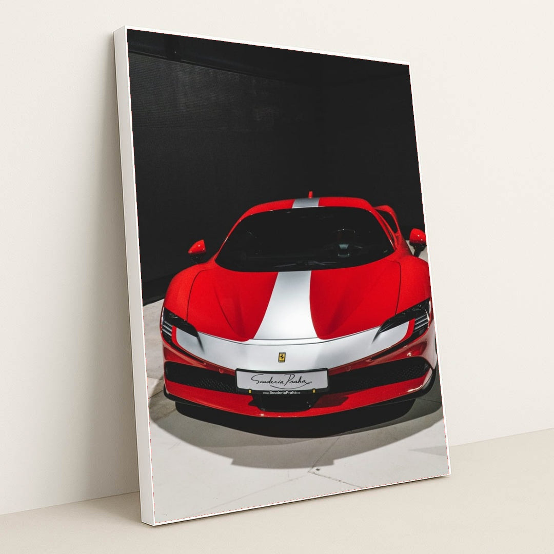 This photo shows a red Ferrari sports car with a white racing stripe parked indoors under direct lighting, in a white frame.