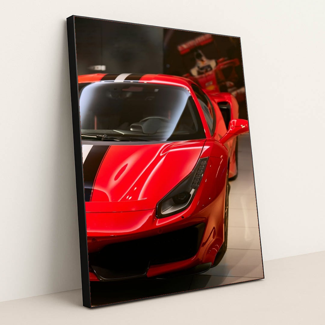 This photo shows the front left side of a red Ferrari with a black and white racing stripe, parked indoors, in a white frame.