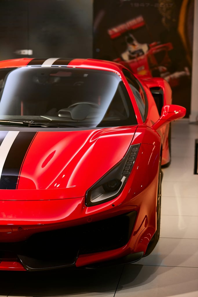 Ferrari 488 Pista in Focus: close-up of red sports car with racing stripes in modern showroom setting, car wall art.