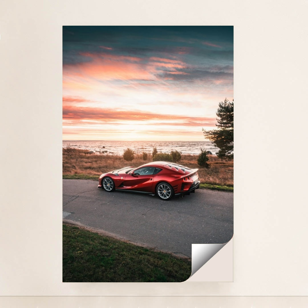 This photo shows a red Ferrari 812 Superfast parked by the seaside at sunset, unframed.