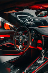 Porsche Interior in Red Glow featuring a sleek driver's seat with carbon fiber accents and red ambient lighting.